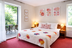 Pokój dwuosobowy z balkonem w Pobierowie, łóżko małżeńskie z kwiatową narzutą